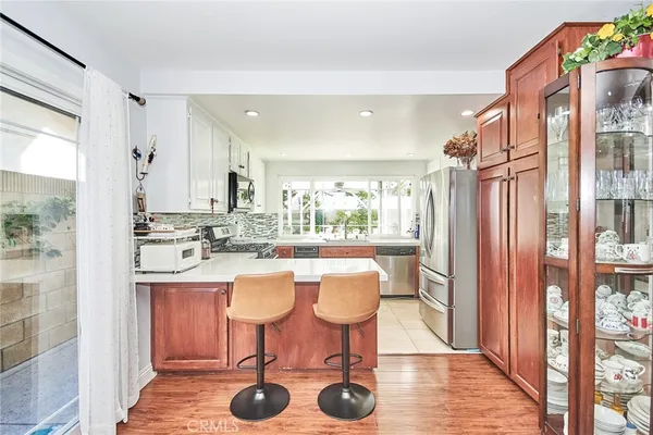 a kitchen with stainless steel appliances granite countertop a refrigerator a stove a sink and white cabinets with wooden floor