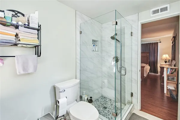 a bathroom with a granite countertop shower a toilet a sink and a mirror
