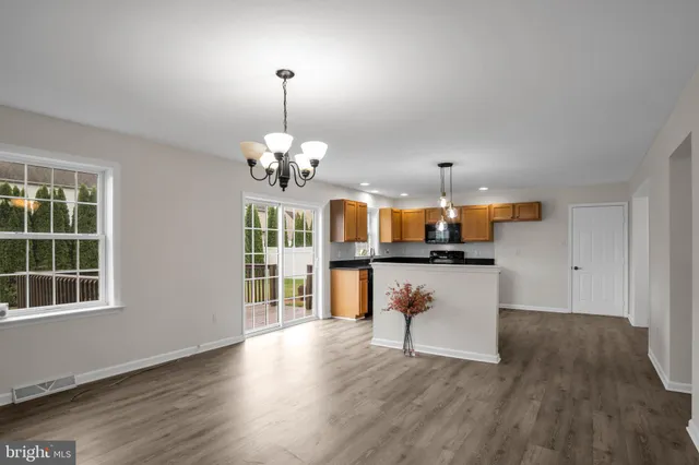 a view of an empty room with wooden floor and chandelier