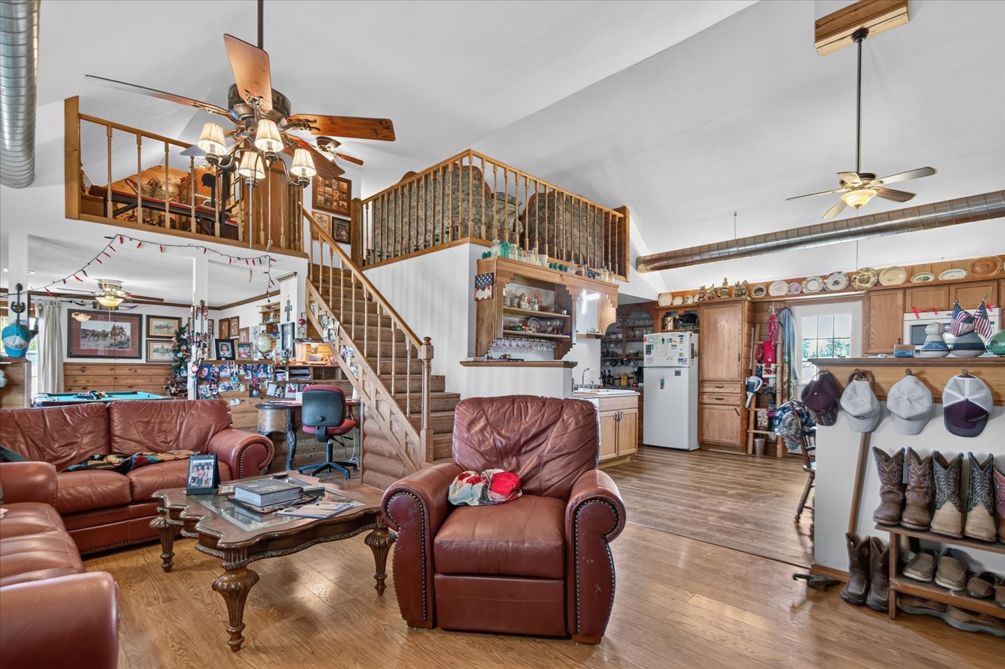26115 4157th Road Nowata, OK 74048 - Photo 8 of 36 Open-concept living space with soaring ceilings, a loft-style mezzanine with wood railing, and hardwood flooring throughout