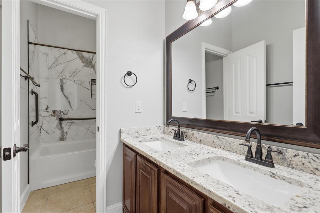 5224 Smokey Ridge Drive Fort Worth, TX 76123 - Photo 23 of 36 a bathroom with a granite countertop sink a mirror and a shower