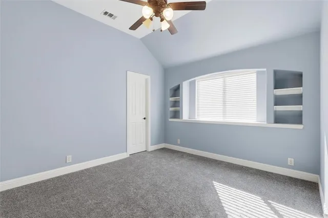 an empty room with a ceiling fan and carpet