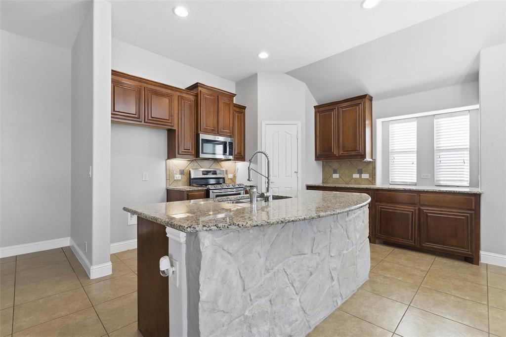 5224 Smokey Ridge Drive Fort Worth, TX 76123 - Photo 8 of 36 a kitchen with kitchen island granite countertop a sink stove and cabinets