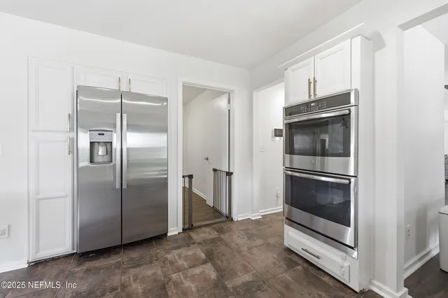 a metallic refrigerator freezer and a stove sitting inside of a kitchen