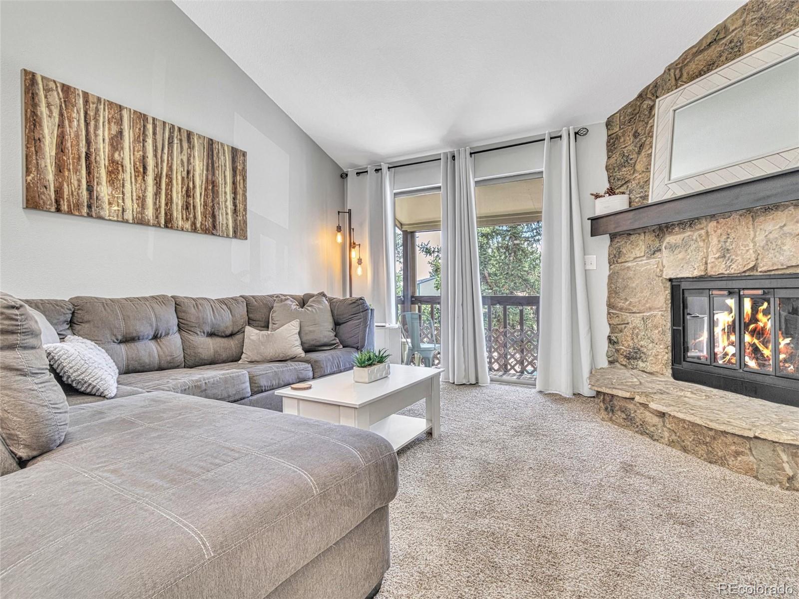 a living room with a couch a fireplace a flat screen tv and a large window