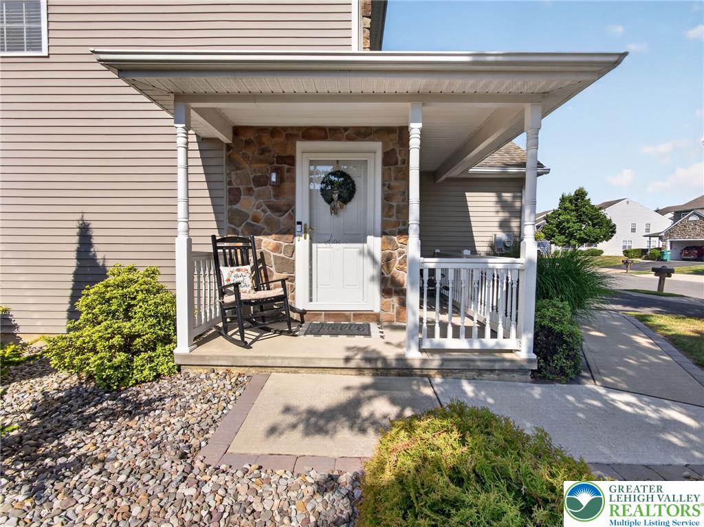 4148 Ross Road Bethlehem, PA 18020 - Photo 17 of 67 A welcoming front porch features stone accents and a classic rocking chair, creating inviting curb appeal.