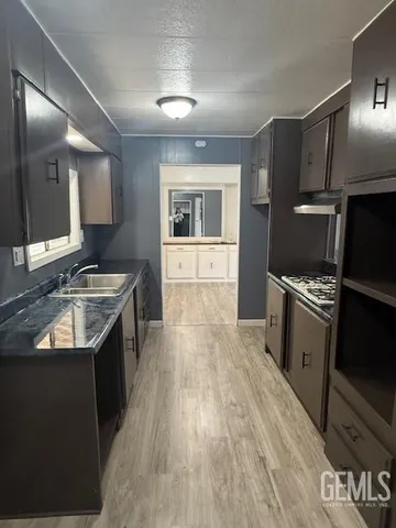 a kitchen with granite countertop a sink stove and refrigerator
