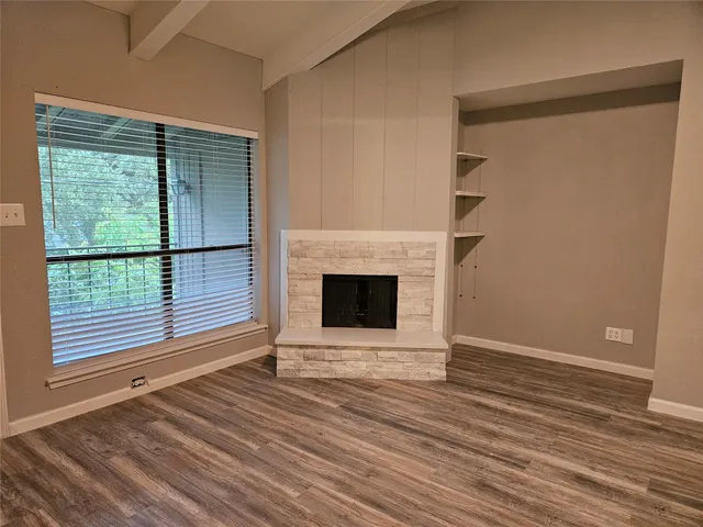 a view of a livingroom with wooden floor and a fireplace