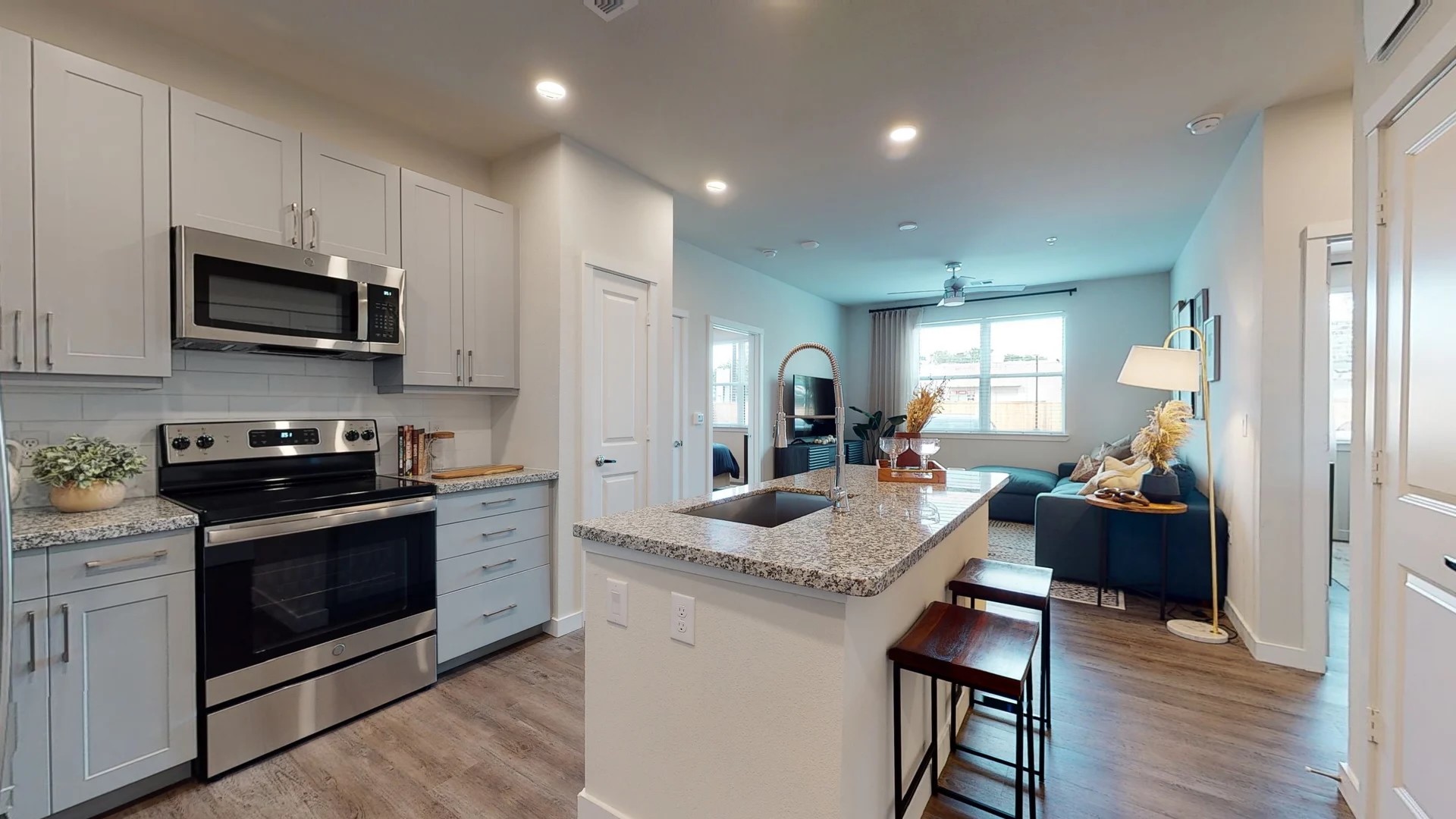 a kitchen with stainless steel appliances granite countertop a sink dishwasher a stove and a refrigerator with wooden floor