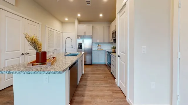a kitchen with kitchen island granite countertop a sink and wooden cabinets