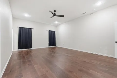 an empty room with wooden floor and ceiling fan