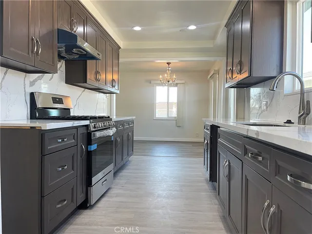 a kitchen with stainless steel appliances granite countertop a sink a stove and a wooden cabinets