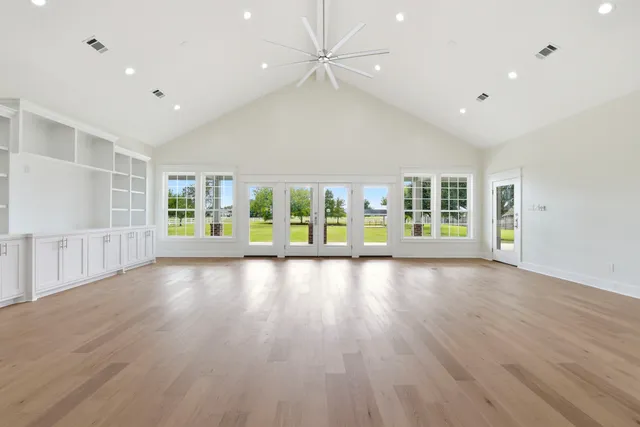 a view of an empty room with a window and wooden floor