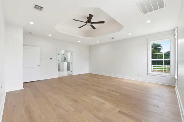 a view of empty room with wooden floor and fan