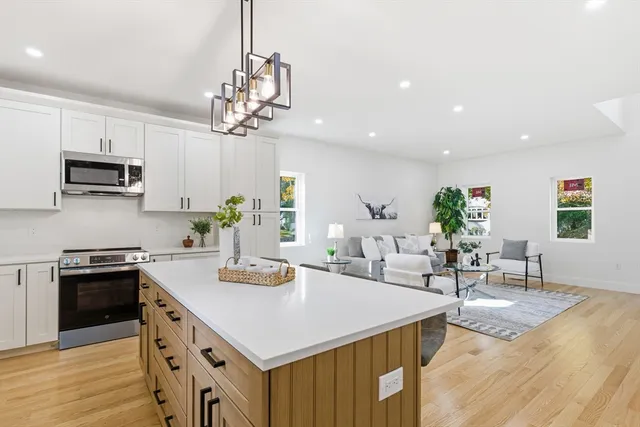 a kitchen with stainless steel appliances granite countertop a sink a stove a dining table and chairs with wooden floor