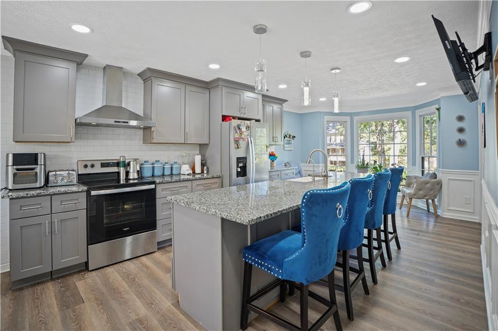 4880 Racquet Court Duluth, GA 30096 - Photo 2 of 22 a kitchen with stainless steel appliances granite countertop a stove a refrigerator a kitchen island a dining table and chairs