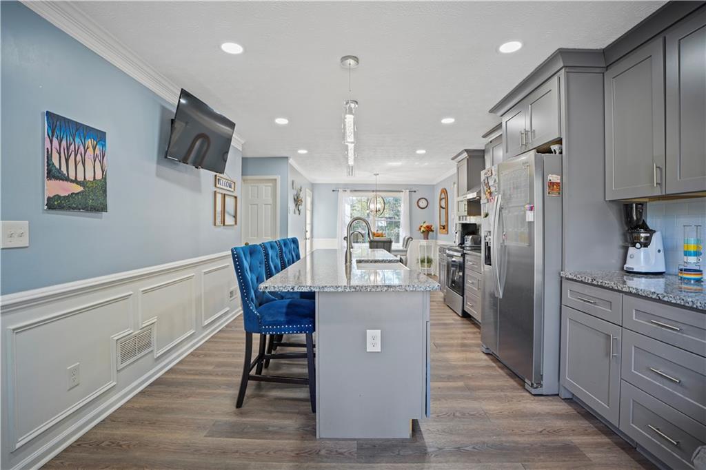 4880 Racquet Court Duluth, GA 30096 - Photo 8 of 22 a kitchen with stainless steel appliances kitchen island granite countertop a refrigerator a stove a sink dishwasher with a dining table and chairs