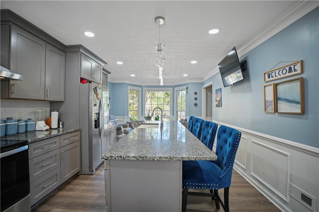 4880 Racquet Court Duluth, GA 30096 - Photo 9 of 22 a kitchen with stainless steel appliances granite countertop a kitchen island a stove a table and chairs