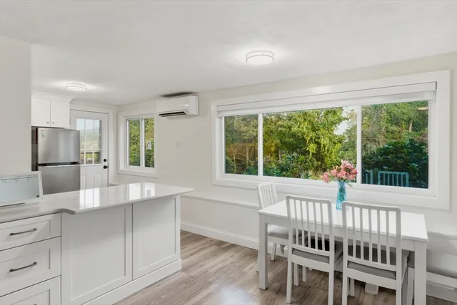 a dining room with wooden floor electric appliances and windows