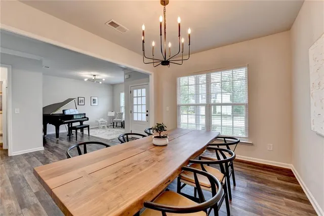 a dining room with wooden floor a chandelier a wooden table and chairs