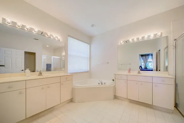 a bathroom with a double vanity sink mirror and bathtub