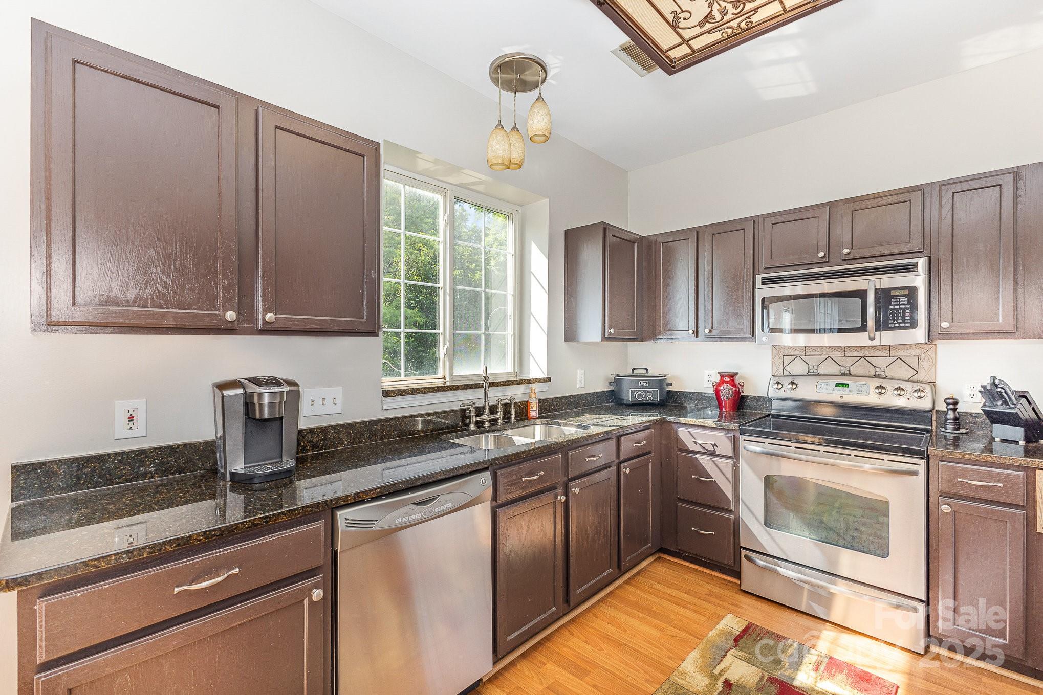 815 Clearbrook Road Matthews, NC 28105 - Photo 9 of 45 a kitchen with stainless steel appliances granite countertop a sink stove and microwave