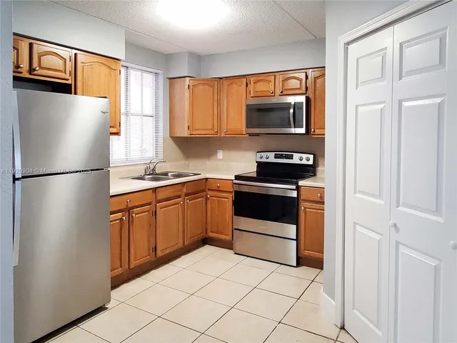 a kitchen with stainless steel appliances granite countertop a refrigerator stove top oven and sink