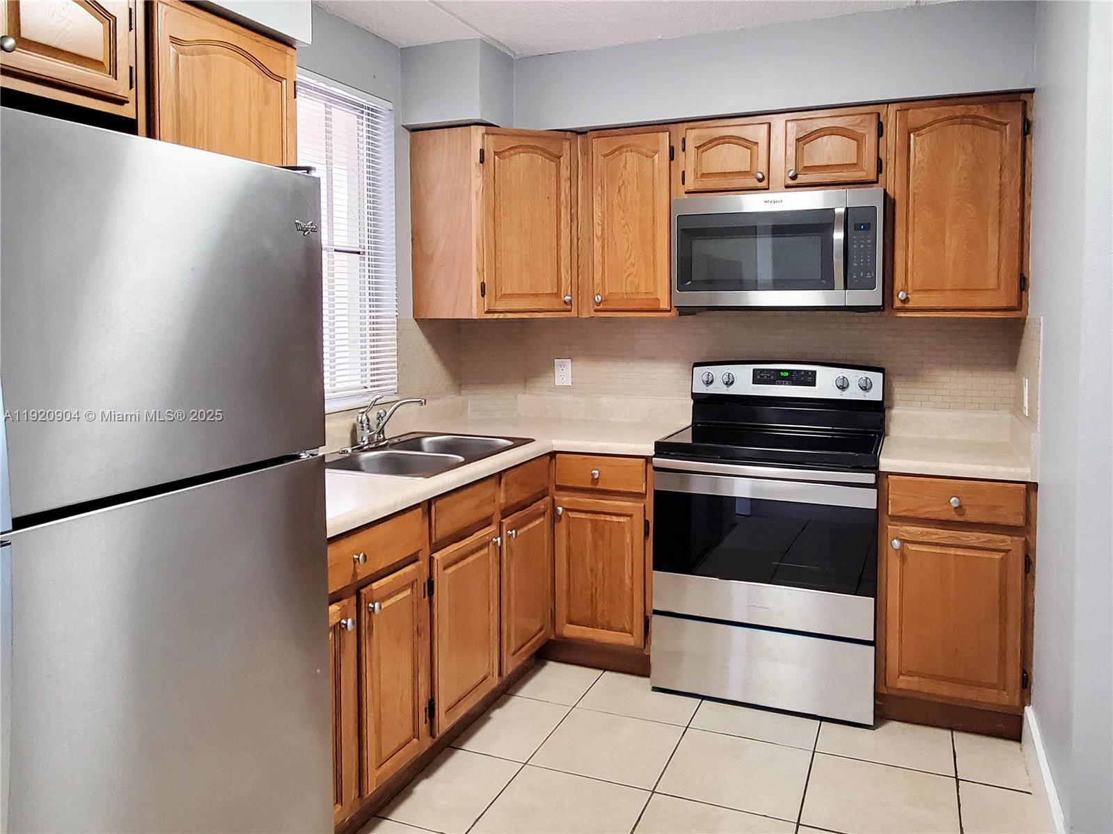 6065 Northwest 186th Street, Unit 106 Hialeah, FL 33015 - Photo 7 of 20 a kitchen with stainless steel appliances a refrigerator stove and microwave