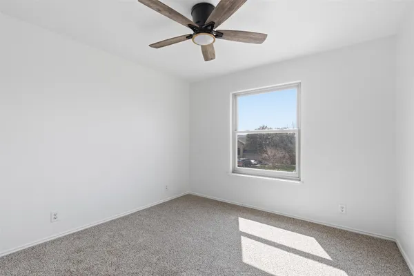 an empty room with a window and a fan