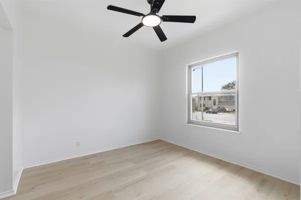 an empty room with chandelier fan and windows
