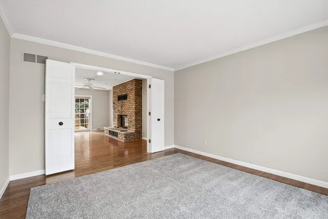 a view of an empty room with wooden floor and a fireplace