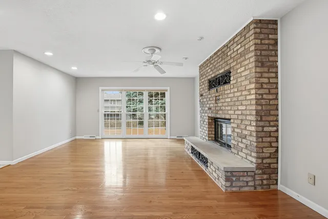 an empty room with wooden floor a fireplace and windows