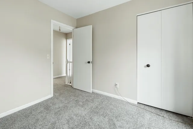 an empty room with a chandelier fan and windows