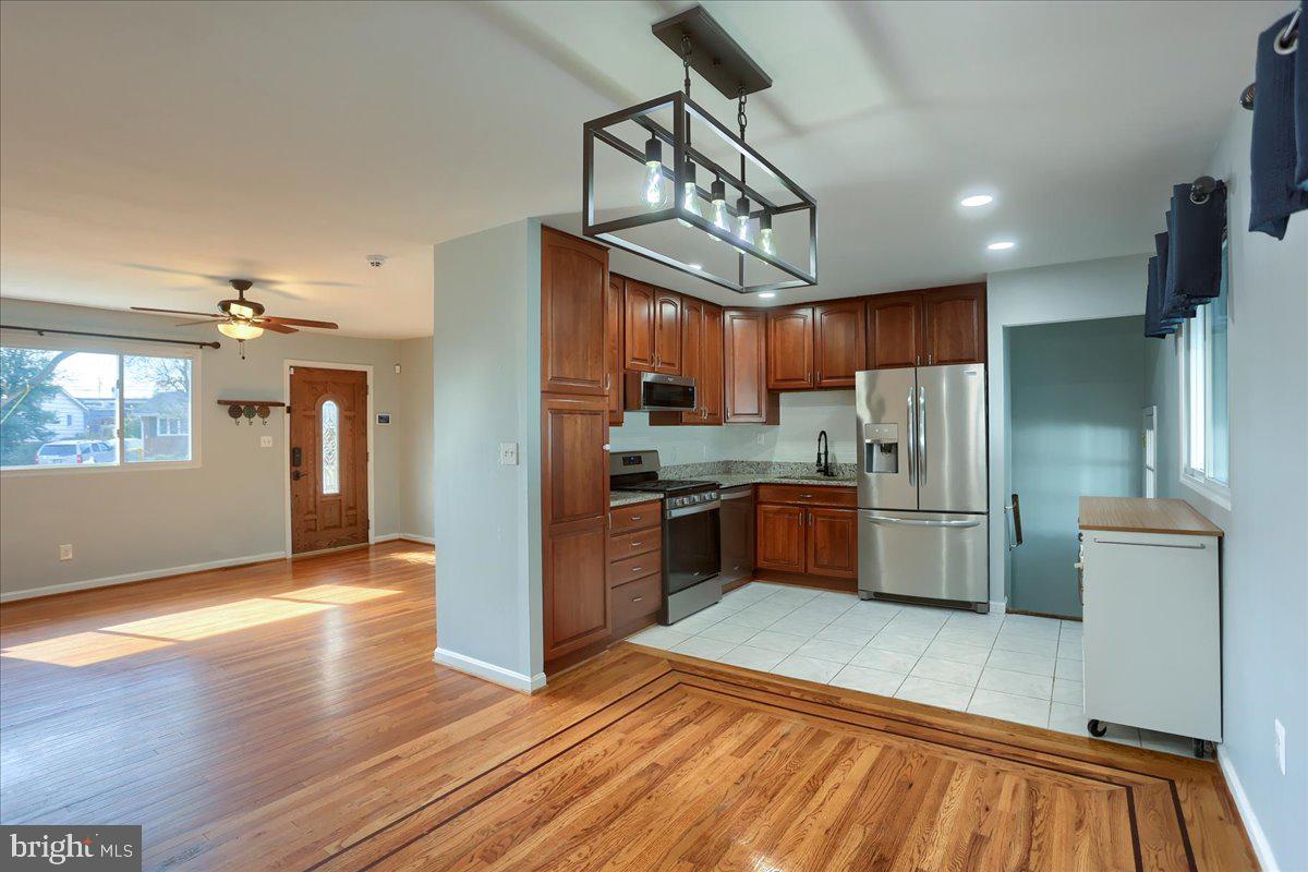 104 Cedarcliff Court Glen Burnie, MD 21060 - Photo 8 of 34 a kitchen with stainless steel appliances a refrigerator a sink dishwasher a stove and white countertops with wooden floor
