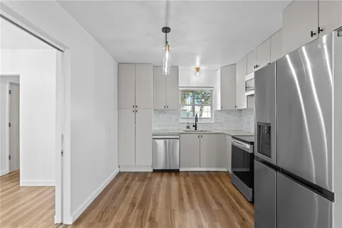 a kitchen with sink a refrigerator and wooden floor
