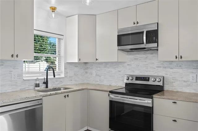 a kitchen with stainless steel appliances granite countertop white cabinets granite counter tops and a window