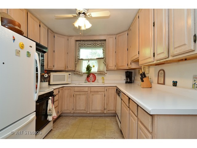 401 Warren Road Glenview, IL 60025 - Photo 5 of 10 a kitchen with kitchen island white cabinets and white appliances