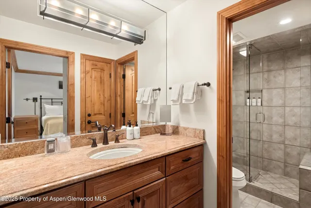 a bathroom with a granite countertop sink a mirror and a shower