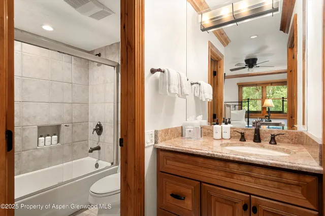 a bathroom with a granite countertop sink a toilet a bathtub and shower