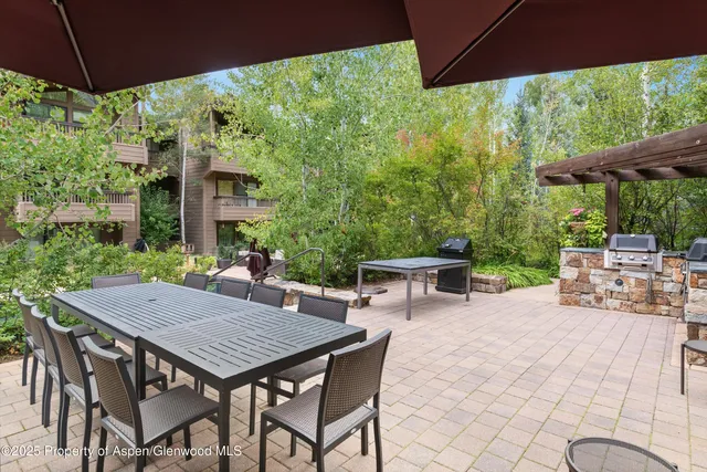 a backyard of a house with table and chairs under an umbrella