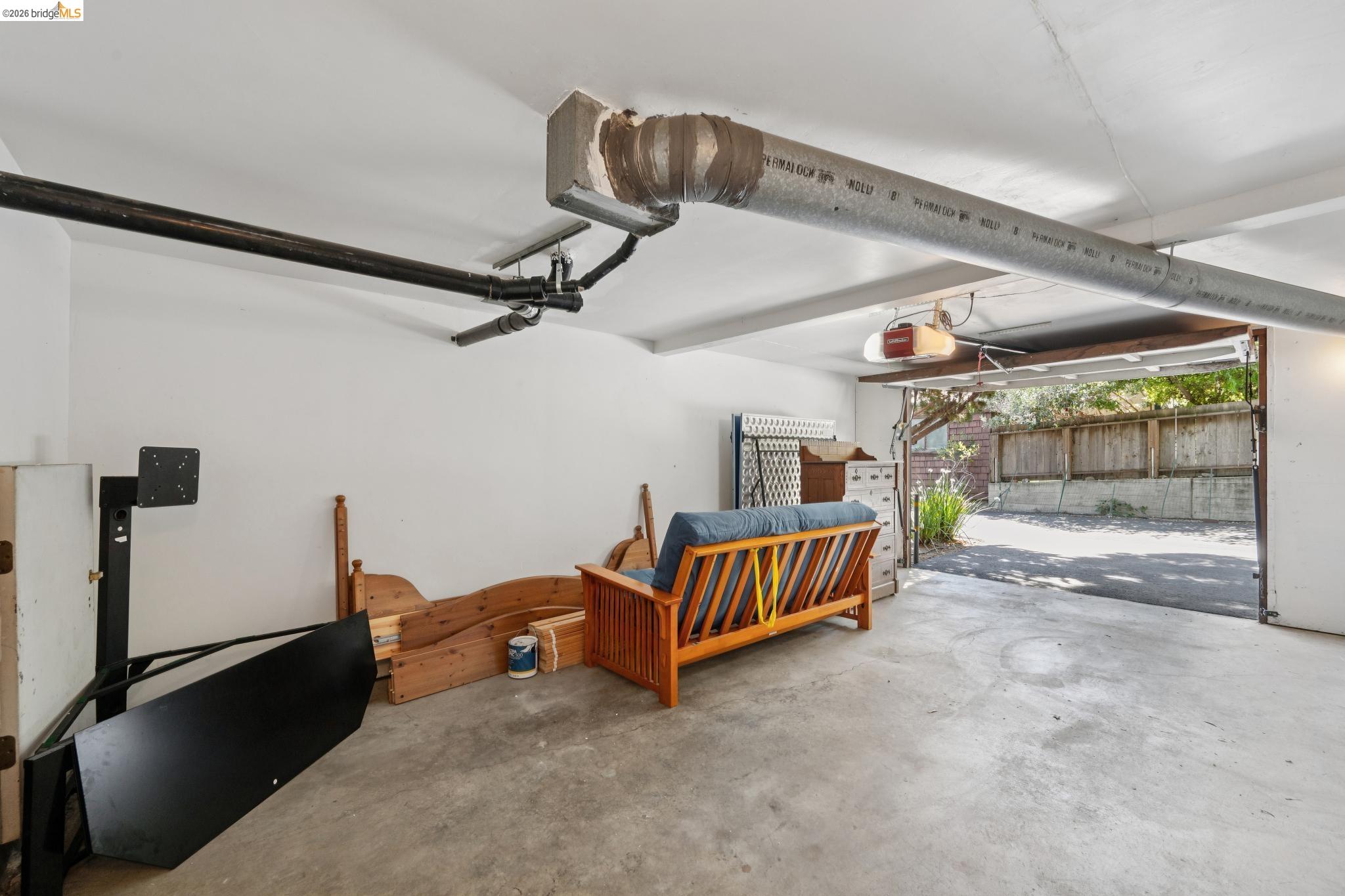 1340 Henry Street Berkeley, CA 94709 - Photo 50 of 52 Attached garage with a concrete floor, white painted walls, exposed ceiling beams, and an automatic garage door opener