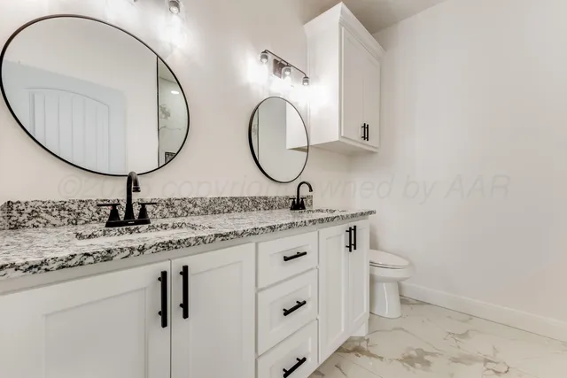 a bathroom with a granite countertop double vanity sink and a mirror