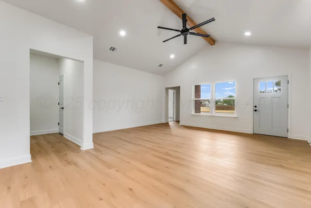 a view of empty room with wooden floor and ceiling fan