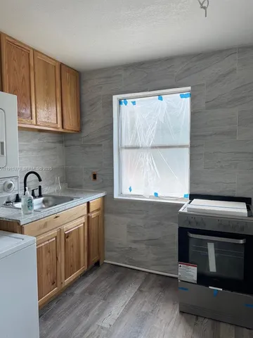 a kitchen with stainless steel appliances a stove a sink and white cabinets with wooden floor