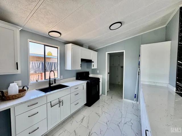 a kitchen with granite countertop a refrigerator stove top oven and sink