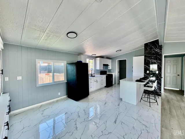 a kitchen with stainless steel appliances kitchen island granite countertop a refrigerator and a sink