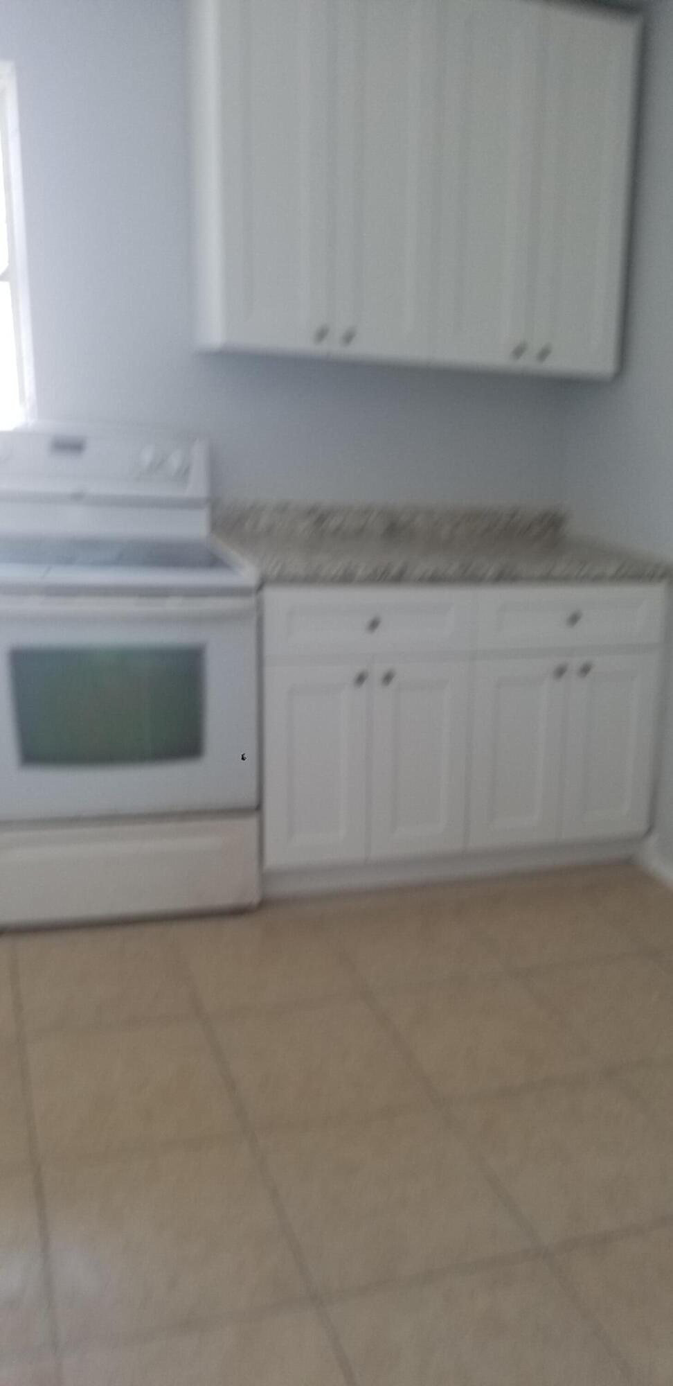 919 6th Street, Unit 15 West Palm Beach, FL 33401 - Photo 15 of 35 a kitchen with white cabinets and a fireplace
