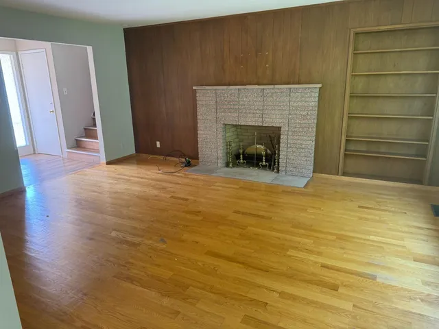 a view of empty room with wooden floor and fireplace