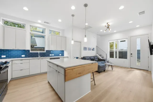 a large kitchen with kitchen island a sink a stove a center island a stove a dining table and chairs