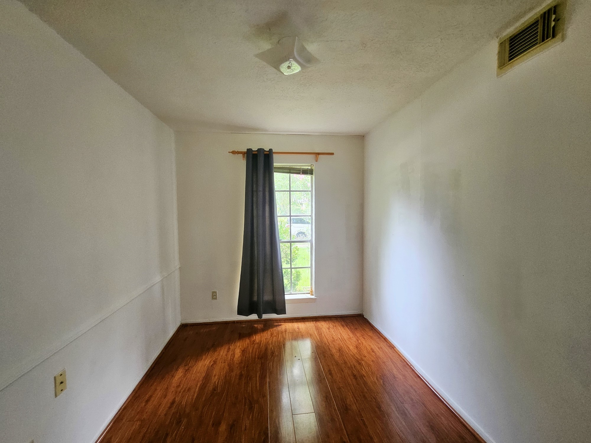 9318 Neff Street Houston, TX 77036 - Photo 4 of 10 an empty room with wooden floor and windows